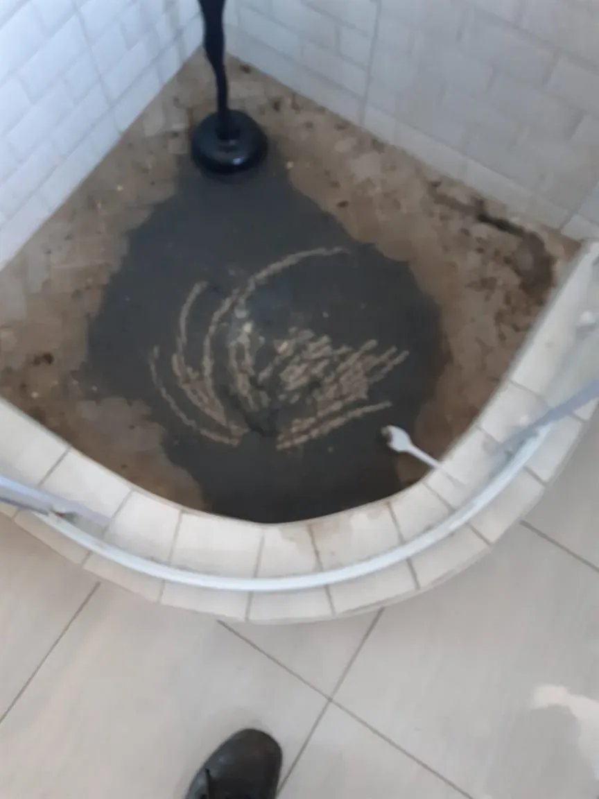 Bathroom drain blockage with standing wastewater before professional cleaning
